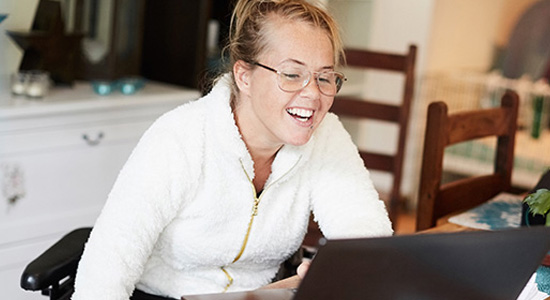 A woman smiles at her computer screen